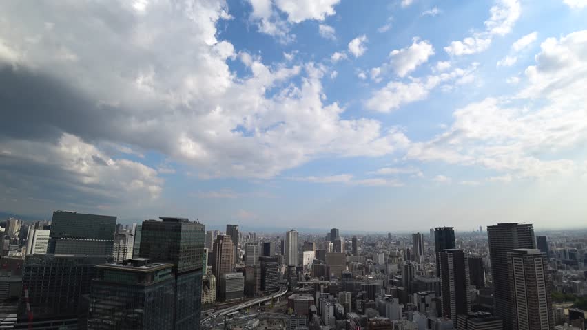 UMEDA, OSAKA, JAPAN - JUNE 2024 : Aerial high angle view around Osaka train station in daytime. View of crowded buildings at downtown area. Urban city and business concept video. Time lapse shot.