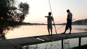 Father and son fishing at dusk by the lake