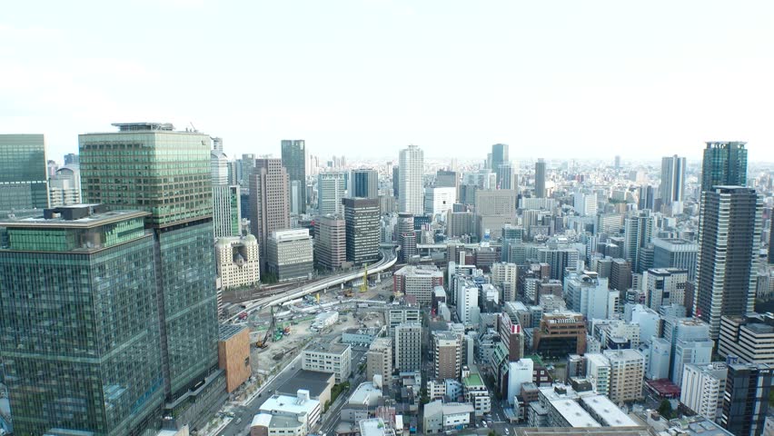 UMEDA, OSAKA, JAPAN - JUNE 2024 : Aerial view around Osaka train station in sunset. View of crowded buildings at downtown area. Urban city and business concept video. Time lapse shot, day to night.