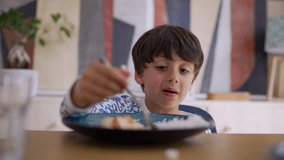 Young boy eagerly eating rice at the table, enjoying a hearty spoonful of food. He is dressed in colorful pajamas - Powered by Shutterstock - Get 15% off with code: PIKWIZARD15