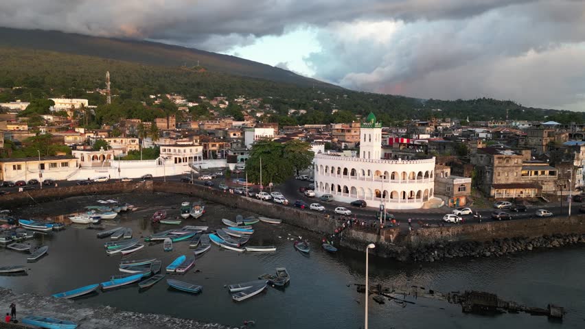 Aerial view showcasing Port Badjanan with empty fishing boats and the Badjanani Mosque in the background in Moroni, Comoros. Dolly Shot