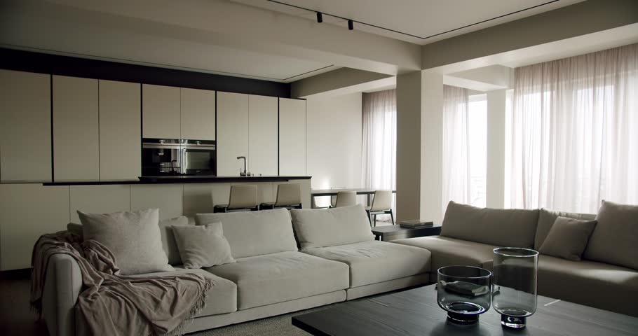 A sleek and stylish modern minimalist living room featuring neutral tones, a comfortable sectional sofa, and a well-organized kitchen area in the background, expressing a sense of serene luxury.