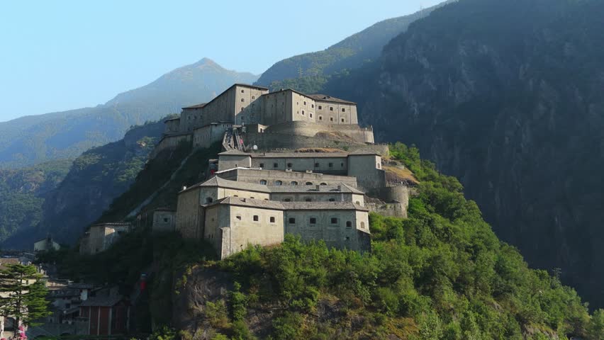Historic Fort Bard in Aosta Valley surrounded by lush green hills and majestic mountains