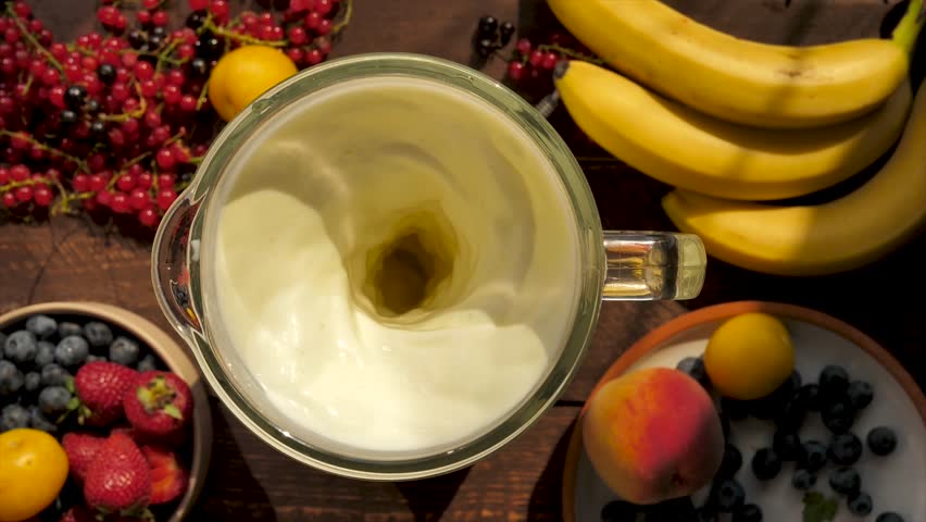 Top view lots of fruits and fresh berries mix in a blender with milk to make a bvnnnew milkshake. Healthy smoothie from banana and milk. Slow motion rotation of fruit napiska with milk in a blender