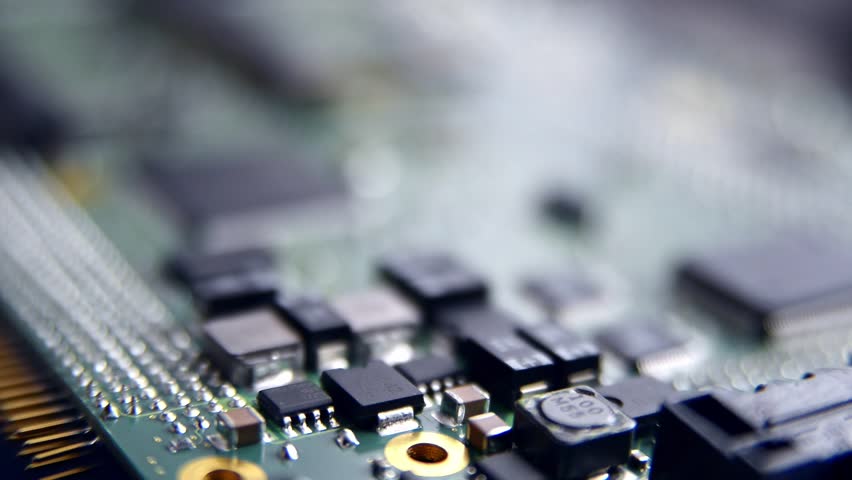 Detailed closeup of an electronic circuit board showcasing microchips, resistors, and other components, representing modern technology and hardware, moving focus gradually.