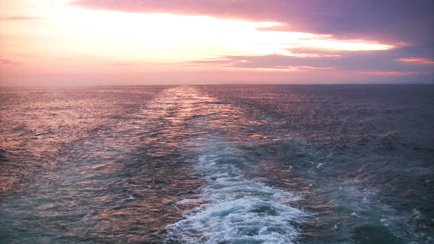 View from the stern of a cruise ship on the multicolored sunset on a cloudy sky.