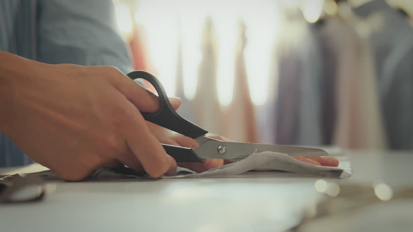 Trendy European woman creating sketches cutting material with sharp scissors in studio. In slow motion, confident girl uses industrial scissors to cut supports fashion trends and styles, tailoring