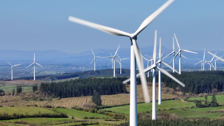 Wind Turbines, Cornasaus, County Cavan, Ireland, April 2023. Drone tracks from left to right with a Telephoto lens as wind turbine blades rotate clockwise with the mountains of Ulster in the distance.
