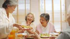Group of Happy Asian senior women having dinner together at home. Elderly retired woman friends enjoy indoor lifestyle meeting party eating healthy food and vegetables salad together on dining table. - Powered by Shutterstock - Get 15% off with code: PIKWIZARD15