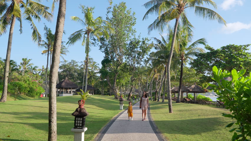 Mother With Toddler Girl Daughter Walking Through Luxury Balinese Tropical Garden at InterContinental Bali Resort Enjoying Vacation