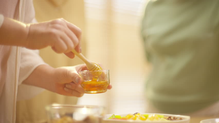 Group of Happy Asian senior women having breakfast together at home. Elderly retired woman friends enjoy healthy lifestyle making homemade greek yogurt with mixed fruit, nuts and honey in the kitchen.