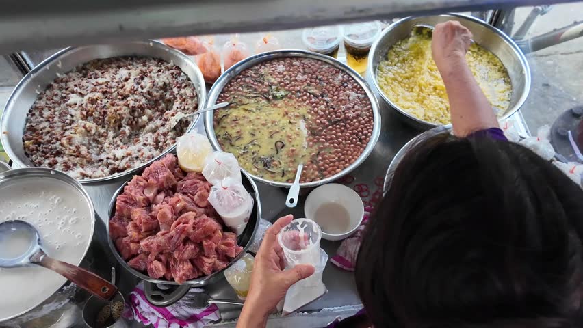 Vietnamese street food, sweet soup is tradition desserts, woman hand scooping che, sugared dishes from deverse bean, banana and coconut milk at outdoor stalls