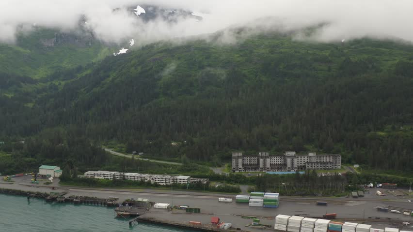 Aerial view of the old U.S. military historic landmark Buckner Building and surrounding mountain area landscape in Whittier, Alaska - 4K Drone