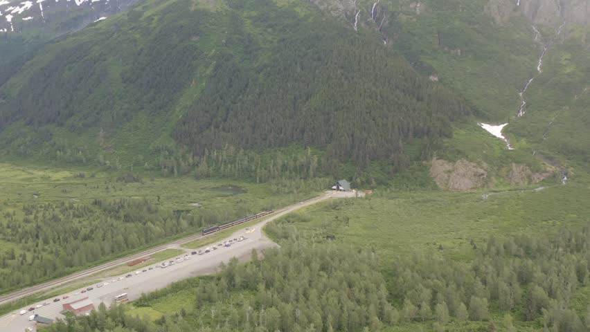 Aerial view of Alaska Railroad passenger train entering the Anton Anderson Memorial Tunnel headed towards Whittier, Alaska - 4K Drone