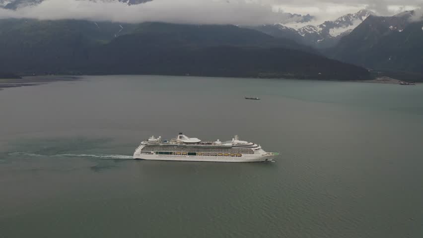 Aerial view of cruiseliner ship leaving harbor port town of Seward, Alaska in Resurrection Bay headed towards Gulf of Alaska - 4K Drone