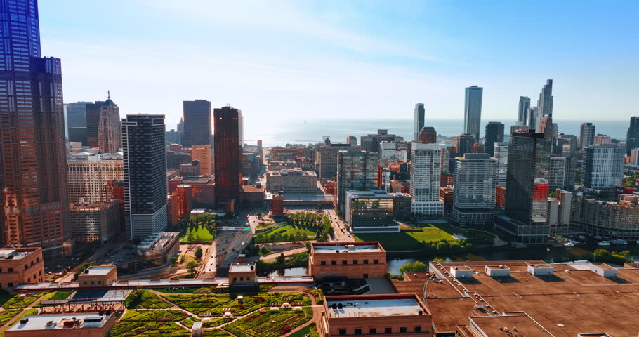 Green parks among the modern architecture of Chicago, Illinois, the USA. Multiple cars ride by the roads of city downtown. Sunny view of the metropolis from top.