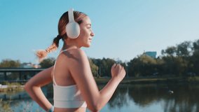 Side view of athletic fitness sport runner girl training, putting on wireless headphones and listening favorite music song. Workout cardio in morning city park. Young woman jogging healthy lifestyle. - Powered by Shutterstock - Get 15% off with code: PIKWIZARD15