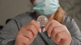 Close-up of a business lady in a medical mask holding a bitcoin coin, an innovative payment network and a new kind of money. Concept of protection against the financial crisis and economic recession. - Powered by Shutterstock - Get 15% off with code: PIKWIZARD15