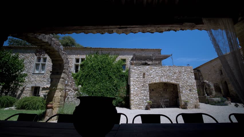 Stone house with a terracotta roof, arched windows, and a patio with a wooden table