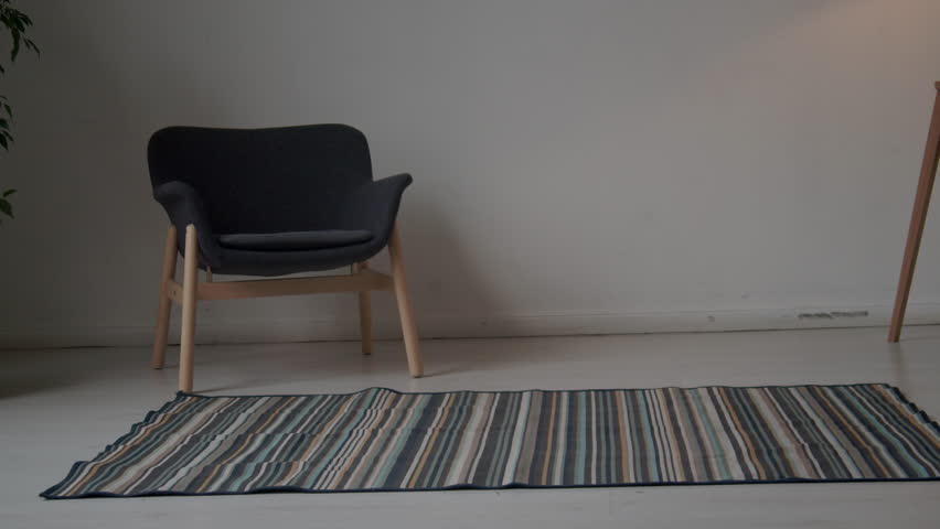 Side low section shot of legs of anonymous man in white pants walking backward and forward in minimalist room