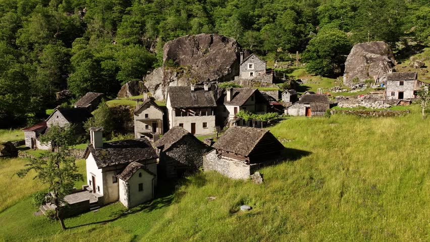 Historical village with stone houses surrounded by lush valley and rock formations in Maggiatal Vallemaggia, Switzerland