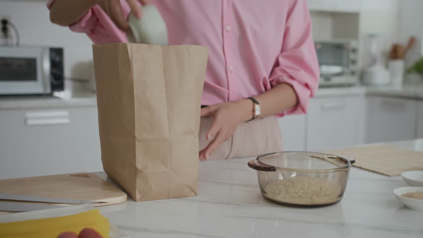 Cropped shot of anonymous woman adding rice to bowl while cooking at home kitchen
