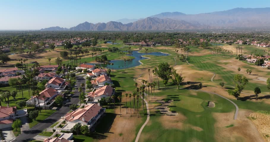 Drone rises above golf course and lake in Palm Springs California USA, panoramic view of homes
