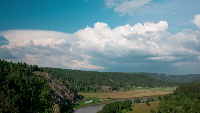 Beauty of clouds drifting over a lush forest and river in a mountain valley, capturing the changing weather patterns and natural scenery. Nature and clouds hyperlapse