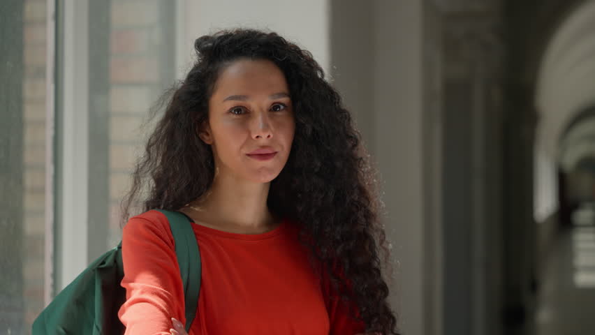 Portrait happy smiling positive Hispanic woman looking at camera student girl Latina female lady in high school university college campus academy hall corridor crossed hands education learning study