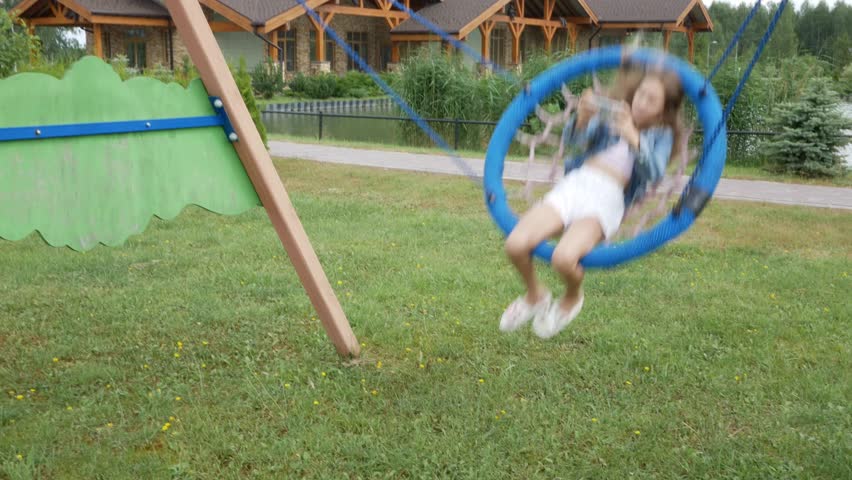Happy child girl on swing at summer. Young teenager girl swinging on a swing using a smartphone and taking selfies on at nature. Lifestyle.