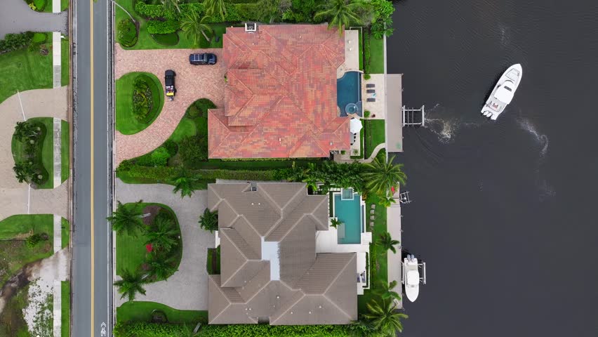 Luxury waterfront home with a pool and private dock in Florida. Yacht cruising on the canal. Aerial top down shot.