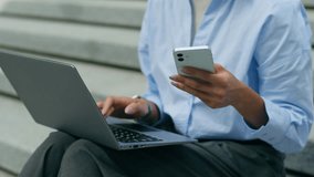 Smiling African American student girl female business woman businesswoman lady sitting in city urban outdoors work online typing laptop pc computer using mobile phone smartphone multitasking chatting - Powered by Shutterstock - Get 15% off with code: PIKWIZARD15