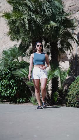 Vertical low angle view of female walk near palm tree and royal castle wall