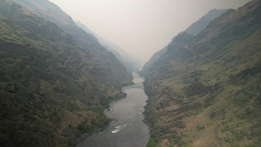 Aerial through hazy Hells Canyon Recreation Area above Snake River with wildfire smoke in Idaho