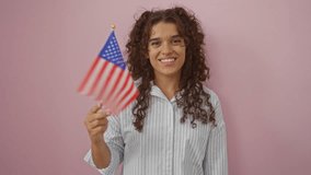 Hispanic woman smiling while holding an american flag against an isolated pink background - Powered by Shutterstock - Get 15% off with code: PIKWIZARD15