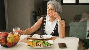 Mature woman having a healthy meal with salad and bread while choosing and eating a fresh apple at home - Powered by Shutterstock - Get 15% off with code: PIKWIZARD15