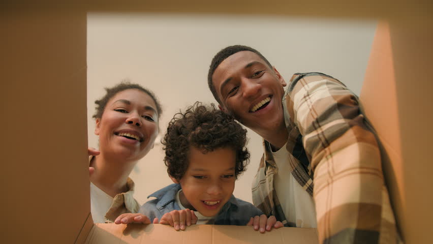 POV point of view inside cardboard box African American family parents little boy kid child open unpack parcel online shopping delivery happy excited mother father son unboxing unpacking moving day
