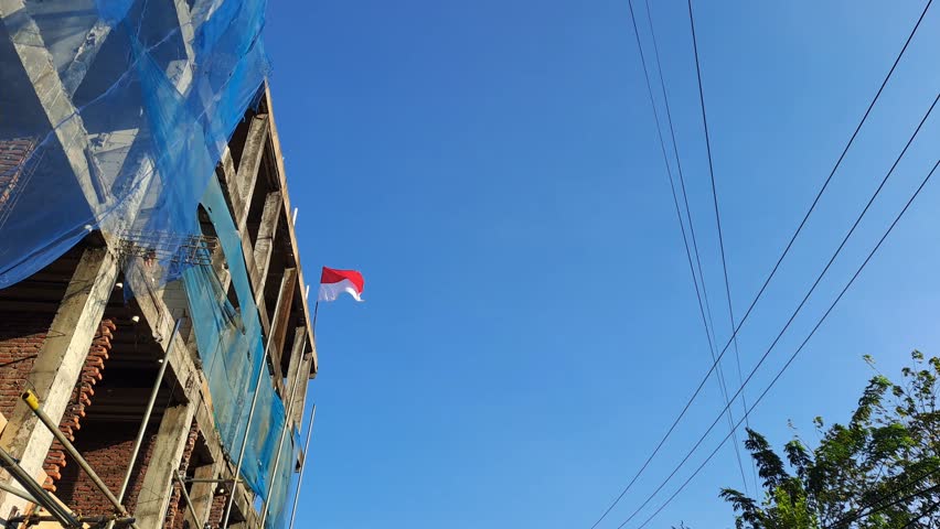Blurred video background of the red and white flag, the Indonesian national flag, is flying above a new building because it is being blown by the wind. The Republic of Indonesia