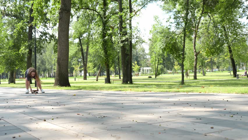  Purposeful teenage girl unsure of how to control her longboard, focused, mastering the thrill of skateboarding in the park
