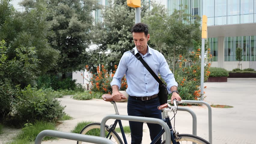 Businessman going to work on on sustainable bicycle transport, parking the bike near office workplace 