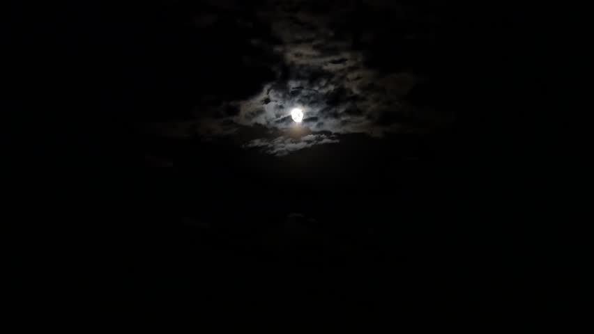 The full disk of the Moon shines on slowly floating clouds in the Gobi Desert on a autumn night.