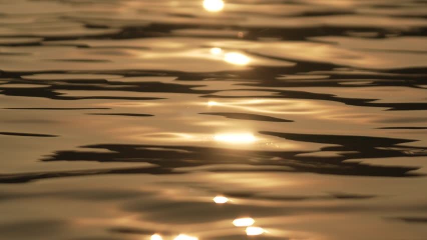 Abstract sea summer ocean sunset nature background. Small waves on golden water surface in motion blur with golden bokeh lights from sun. Holiday, vacation and recreation. Weather and climate change