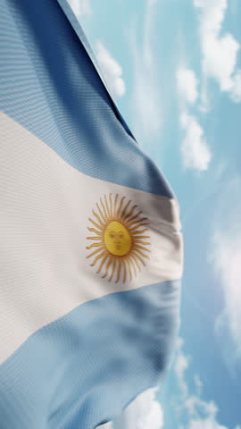 Wavy flag of Argentina blowing in the wind in slow motion. Waving colorful Argentinian flag symbol abstract vertical video background. Sun and blue sky with clouds on a background