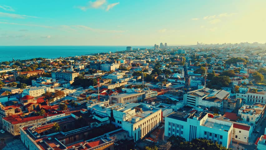 Aerial view of the picturesque seaside city of Santo Domingo during sunset. Sea horizon under the evening sky. Orbital drone shot. Caribbean coastline landscape. Capital of the Dominican Republic.