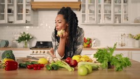 Raw food diet, young black woman biting juicy apple, portrait in kitchen. Healthy nutrition for stay fit and slender, African American lady with dreadlocks eating fruits, table with organic vegetables - Powered by Shutterstock - Get 15% off with code: PIKWIZARD15