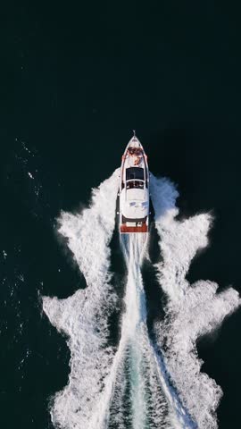 A powerful speedboat cuts through the open sea, leaving a striking wake behind. Captured from above, the scene showcases the thrill of boating and the beauty of the vast ocean