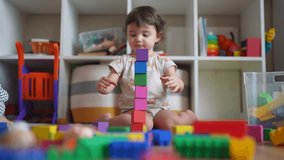 baby plays with toy blocks on floor. development of fine motor skills in children concept. baby daughter girl builds a tower lifestyle from toy cubes indoors kindergarten - Powered by Shutterstock - Get 15% off with code: PIKWIZARD15