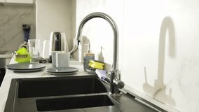 Close-up of a woman's hands turning on the water in the faucet in the kitchen. Slow motion video of water flowing from the faucet into the sink. High quality 4k footage - Powered by Shutterstock - Get 15% off with code: PIKWIZARD15