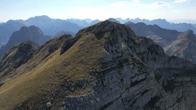 The drone flies up to the top of a mountain illuminated by the sun and surrounded by mountain ranges stretching beyond the horizon - Powered by Shutterstock - Get 15% off with code: PIKWIZARD15