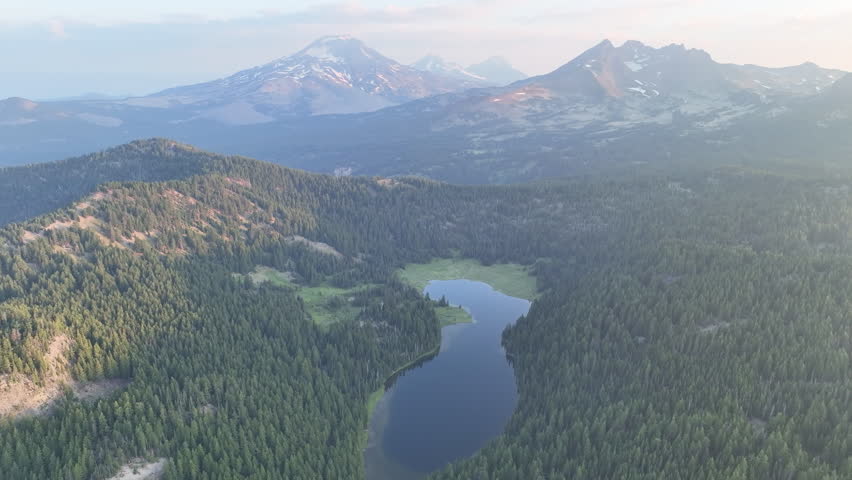 Dawn illuminates Todd Lake and Three Sisters mountains, Oregon, during summer. These mountains and their surrounding forests, near Bend, provide exceptional hiking, biking, climbing, and camping.